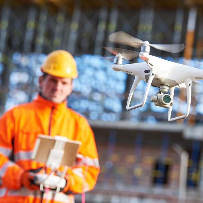 man met oranje jas bedient een drone